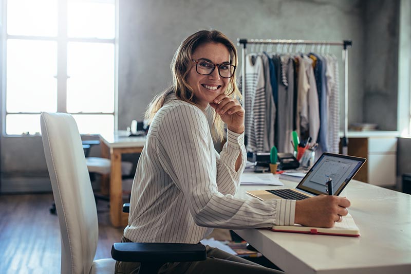 Small business owner at desk with notebook and laptop. 